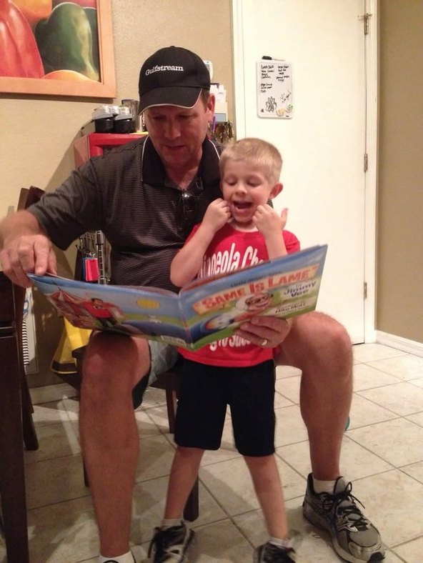 A dad reading Same Is Lame aloud to his young child at home